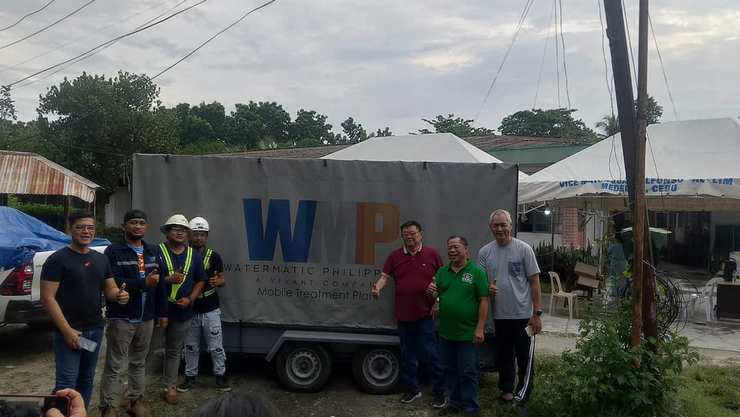 Workers standing posing with locals in front of a WMP unit.